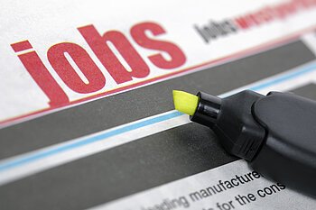 Stellenangebote Zeitungsseite mit dem Wort "Jobs" in großen roten Buchstaben und einem gelben Textmarker daneben.
