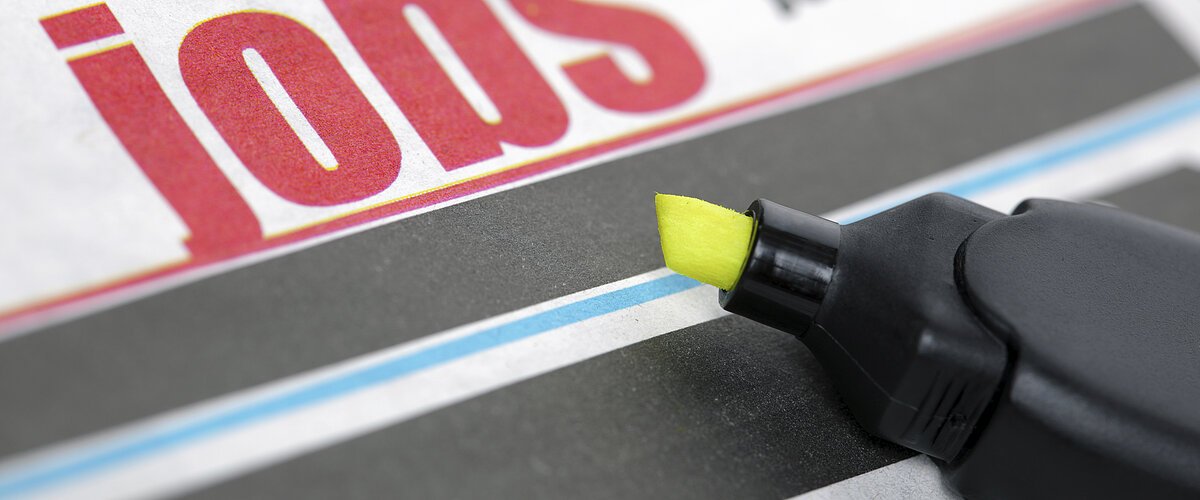 Zeitungsseite mit dem Wort "Jobs" in großen roten Buchstaben und einem gelben Textmarker daneben.